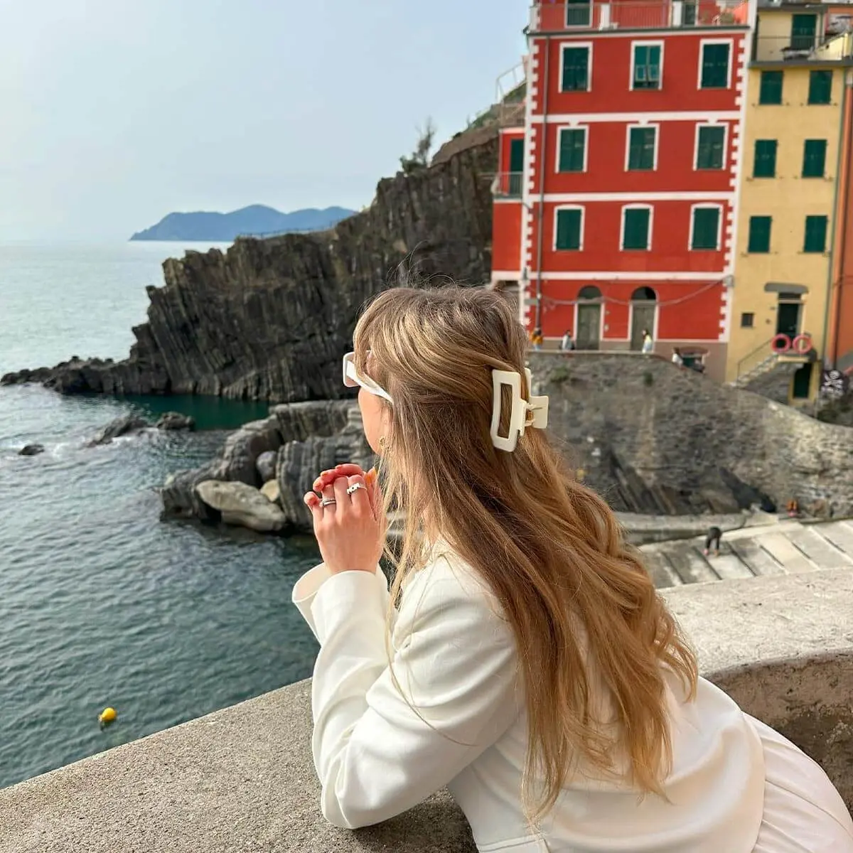 Mädchen in Italien mit halboffenem Haar, gestylt mit einer cremeweißen mittelgroßen Haarklammer, und gekleidet in einen passenden cremeweißen Blazer.